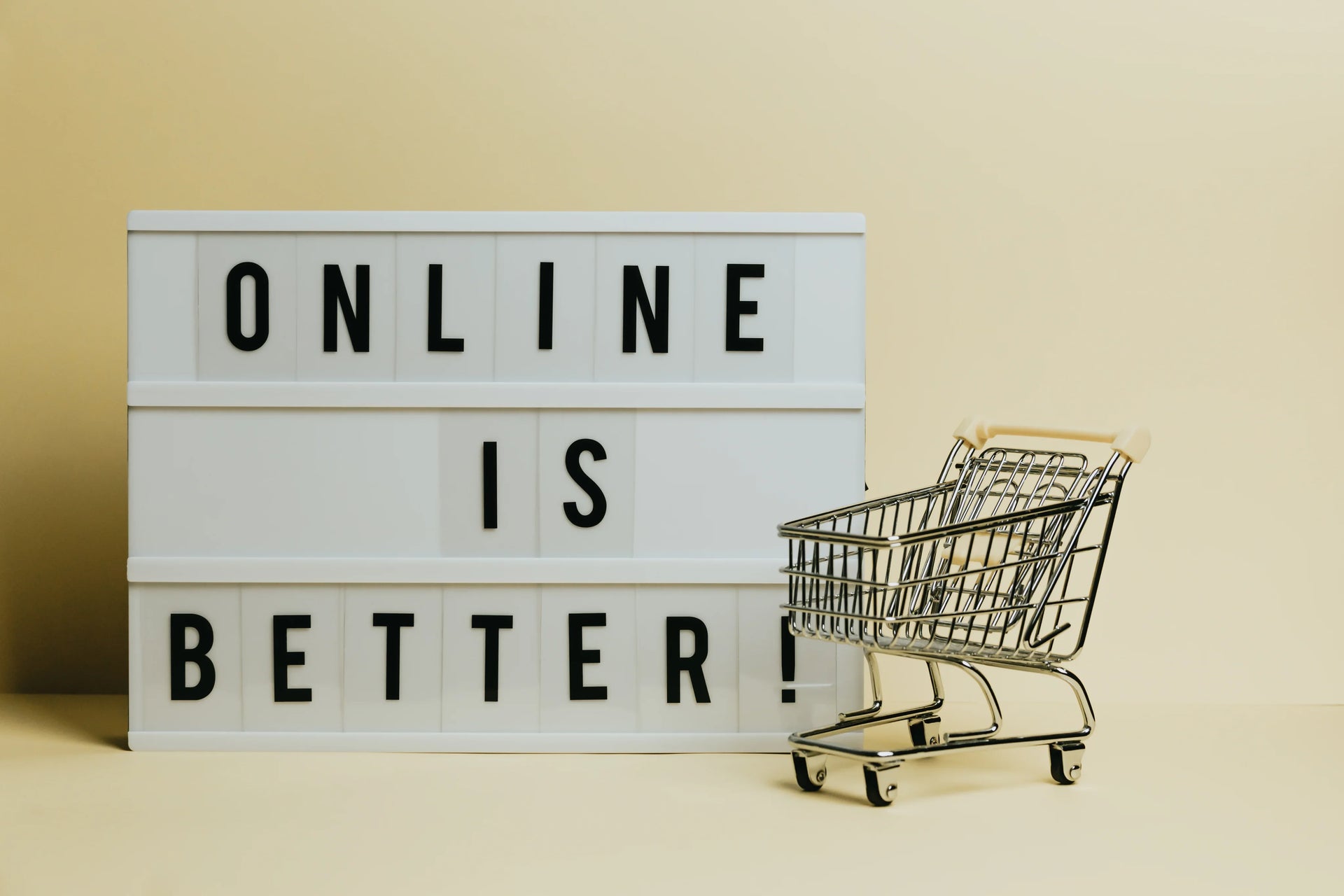 Lightbox sign reading 'Online is better' with a small shopping cart on beige background.
